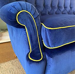 Neubezug eines dreisitzigen Sofas mit Rückenheftung in blauem Samtbezug. Die Keder an Schatose und Sitzkissen wurden als Kontrast in einer leuchtenden Farb gewählt. Die Sitzkissen wurden mit Enten- und Gänsedaunen gefüllt. 